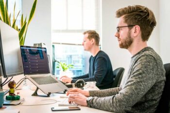 Zwei Mitarbeiter sitzen im Büro vor dem Computer