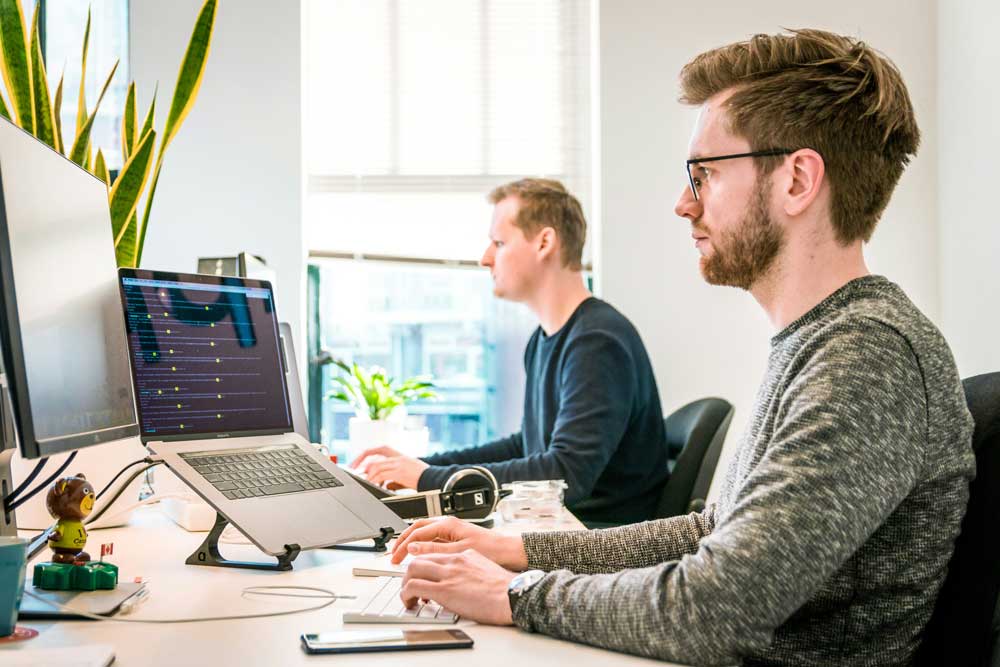 Zwei Mitarbeiter sitzen im Büro vor dem Computer